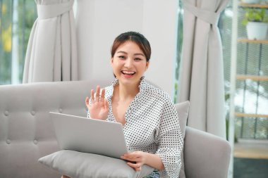 Neşeli güzel bayan bilgisayarını kullanarak arkadaşlarıyla internetteki fotoğraflarında sohbet ediyor.