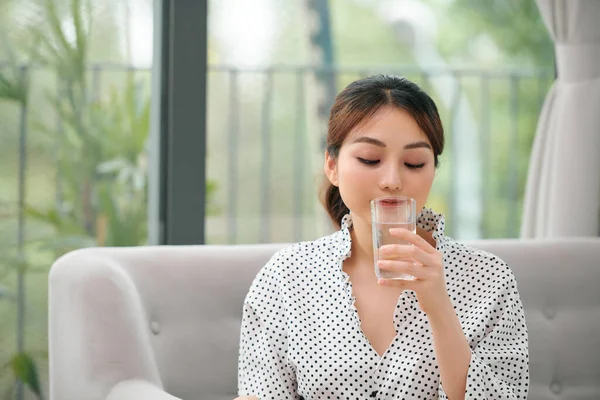 Mujer Bebiendo Agua Casa Mirándote Sentada Sofá Sala Estar Casa — Foto de Stock
