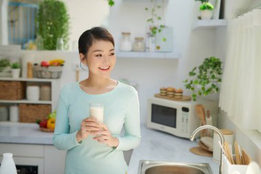 Gülümseyen çekici kadın mutfağın içinde kahvaltı yapıyor.