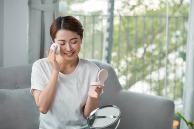 Mutlu genç bir kadın aynaya bakarken kızarıyor.