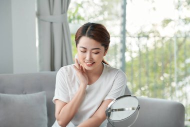 Cildine toner sürerken pamuk pedi kullanan güzel genç bir kadın.