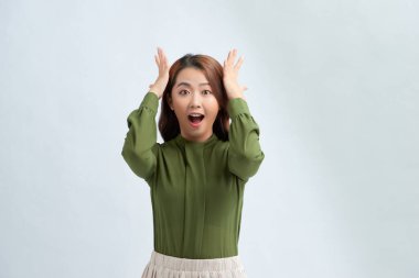 Şaşırmış genç bir kadın başını elinde tutuyor.