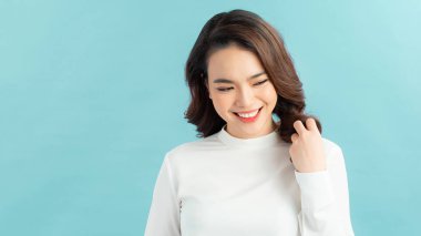 Güzel, neşeli, sarışın, sıradan giyinmiş, kameraya tatmin olmuş, mutlu bir şekilde bakan bir kadın.