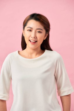 Genç çalışan kadın gülümsüyor ve kameraya bakıyor, pembe arka planda duruyor.. 