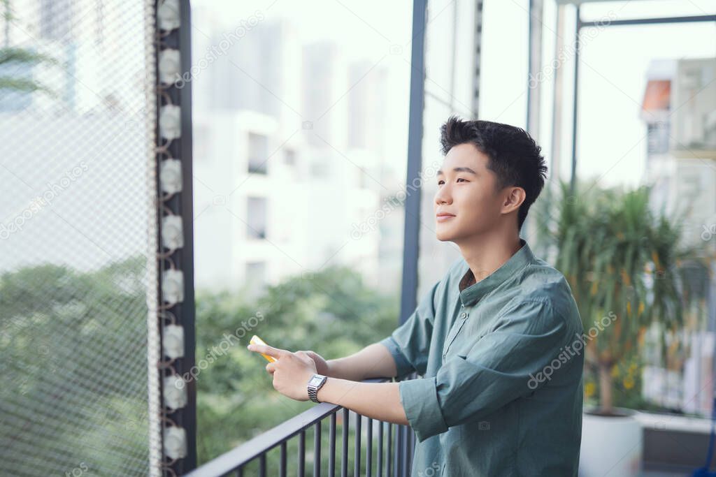 Side portrait of smiling asian man using cellphone