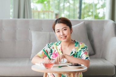 Oturma odasında dinlenen ve günlüğe bir şeyler yazan fikirlerle dolu tatlı, şehvetli bir kadın..