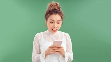 İzole edilmiş mavi arka planı olan genç bir kadın şaşırdı ve bir mesaj gönderiyor.