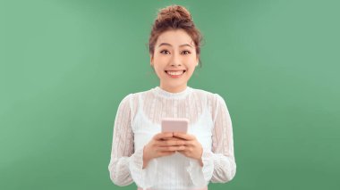 Çekici Asyalı kız cep telefonu kullanıyor, mesajlaşıyor, mesajlaşıyor, arkadaşlarıyla sohbet ediyor, gülmeye başlıyor.