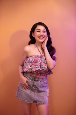 Parlak parlak makyajlı güzel bir genç kadının portresi karışık renkli neon ışıkla poz veriyor.