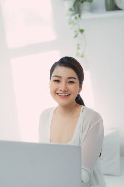 Soğuk bir kış günü yatak odasında dizüstü bilgisayar kullanan genç bir kadın..