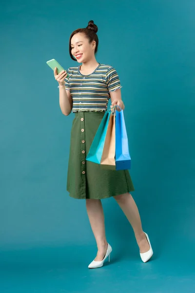 笑顔若いですアジアの女性でショッピングカラーバッグ上の青の背景 — ストック写真