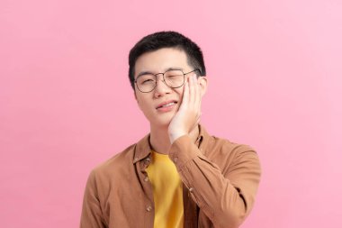 Genç adam yüzüne dokunuyor ve korkunç bir ifadeyle gözlerini kapıyor. Sağlık sorunu ve ağrıyan diş yüzünden acı çekiyor.