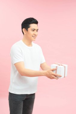 Beyaz tişörtlü, gülümseyen ve hediye kutusu veren pozitif cömert bir adamın yan görünümü.