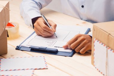 Masadaki karton kutuya yazı yazan kurye elleri. 