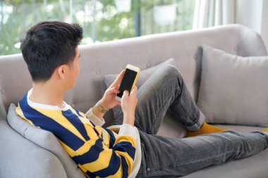 Mutlu bir Asyalı adam güzel bir gülümsemeyle cep telefonuna bakıyor ve mutlu bir anında biriyle sohbet ediyor.