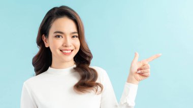 Parmakla işaret eden gülümseyen kadın. Mavi üzerine izole edilmiş portre.