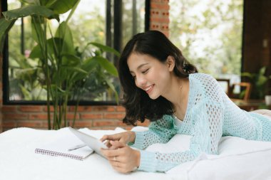 Kalem ve defteriyle yatak odasında yazan mutlu genç bir kadın. 