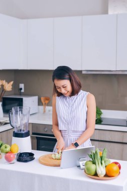 Sağlıklı Asyalı kadın evde blender ile yeşil sebze detoks arındırma ve yeşil meyve püresi yapmaktan hoşlanıyor. diyet konsepti. Sağlıklı yaşam tarzı.