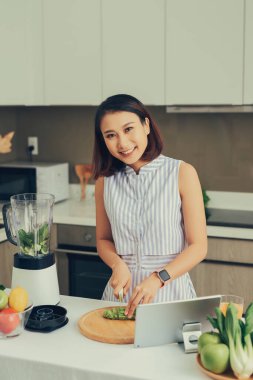 Sağlıklı Asyalı kadın evde blender ile yeşil sebze detoks arındırma ve yeşil meyve püresi yapmaktan hoşlanıyor. diyet konsepti. Sağlıklı yaşam tarzı.
