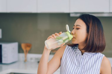 Mutfakta detoks içen Asyalı genç bir kadının portresi. Sağlıklı konsept, kilo kaybı gıda konsepti.