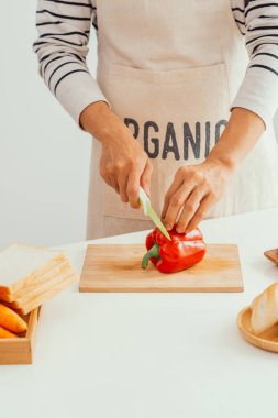 Erkek elleri mutfakta keskin bıçakla taze biber kesiyor.