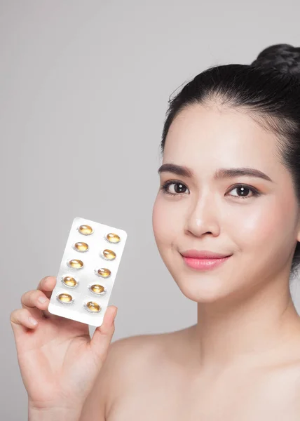 Healthy happy asian woman with pills in hand.