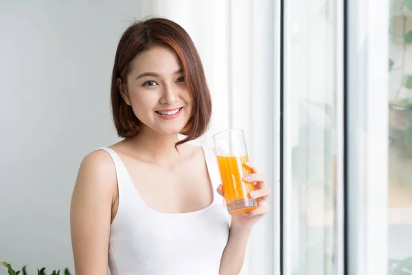 Красивая Молодая Азиатка Светлой Комнате Пьет Апельсиновый Сок — стоковое фото