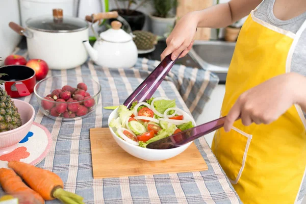 Young asian woman making salad in kitchen smiling and laughing happy at home.