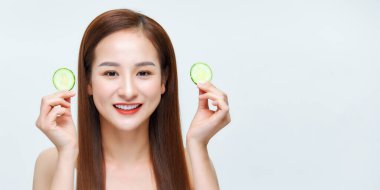 Güzel bir kadın salatalık dilimleriyle oynuyor ve gülümsüyor, cilt pürüzsüzlüğünü geliştiriyor.