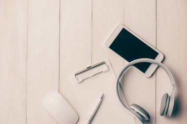 Not defteri ve akıllı telefon beyaz masada, kulaklıklı. Yukarıdan görüntüle