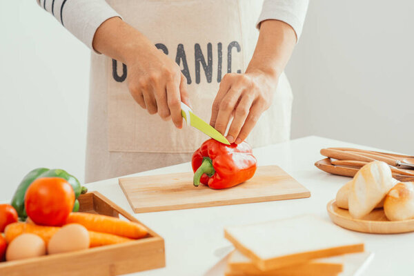 Man hands cutting fresh peppers with sharp knife in kitchen