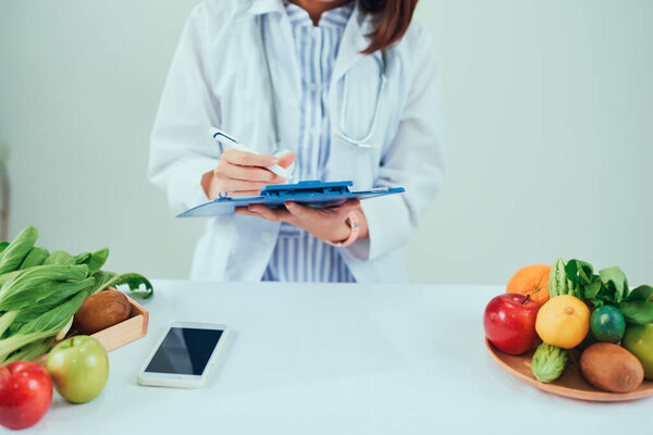 Portrait of young smiling female nutritionist in the consultation room. Dietitian working on diet plan.