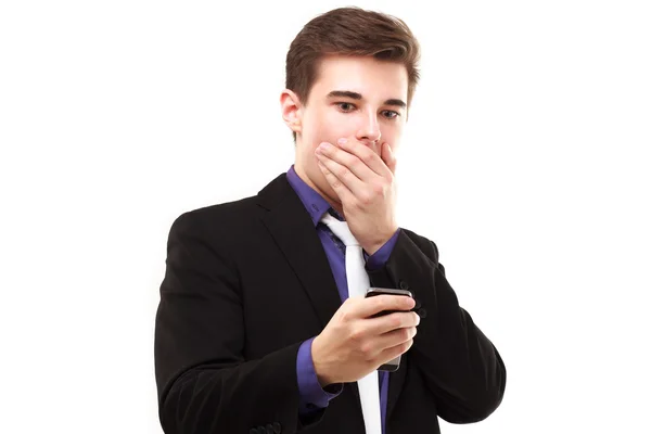年轻的商人害怕地看着手机，涵盖了他的嘴 免版税图库照片