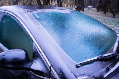 Park halindeki araba şeffaf bir buz kabuğuyla kaplıdır. Kış havası sürprizleri. Sıcaklıktaki keskin düşüş yağmur damlalarını dondurmuş, her şeyi kaygan buzla kaplamış..