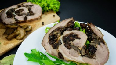 Köfte domuz eti, kuru erik ve mantarla dilimlenmiş körfez yaprakları, roka, siyah arkaplanda marine edilmiş mantarlar. Etli sandviç ve beyaz tabakta otlar..