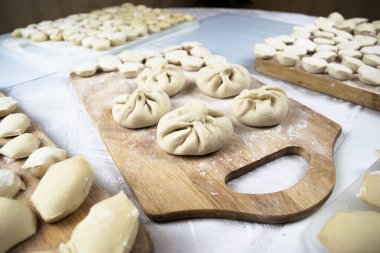 El yapımı hamur köfteleri, ravioli ve khinkali beyaz arka planda un serpiştirilmiş tahtalara güzelce serilmiştir. Lezzetli ev yapımı yemekler ve hazırlıklar..