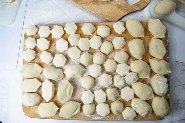 手工饺子 精美地摆放在用面粉撒在白色背景上的切碎板上 美味的自制食品和制剂 — 图库照片