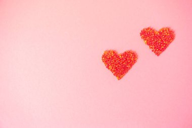 Aşkın sembolü olarak boncuktan yapılmış iki kırık kalp izole edilmiş, açık pembe bir arka planda. Sevgililer Günü için tebrik kartı, Anneler Günü ya da diğer tatiller için. Seçici odaklanma. Düz yatıyordu. Boşluğu kopyala.