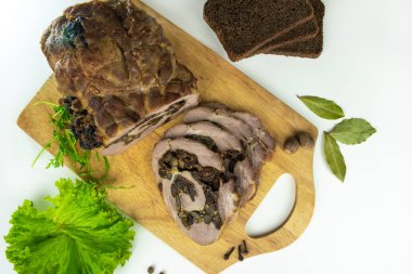 Baharat, defne yaprakları, roka ve beyaz arka planda dilimlenmiş ekmek dilimleriyle süslenmiş kesilmiş kuru erik ve mantarlı fırında köfte..