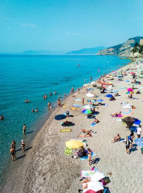 Final Ligure, İtalya - 23 Temmuz 2019: Özgür kumlu ve çakıl taşlı Capo San Donato veya Castelleto Pier Sahili üzerinde tatilciler sakin Akdeniz yakınlarında güneşli bir günde. Ligurian Riviera Sahili.