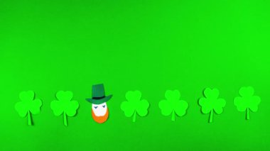 Yeşil arka planda 4k Shamrock yaprakları ve leprikonlar. 17 Mart 'ta kutlanan Aziz Patrick Günü için tebrik kartı. İrlanda kültürel bayramı. Hareket animasyonunu durdur. Boşluğu kopyala.
