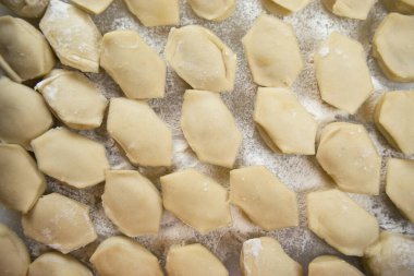 El yapımı hamur köfteleri kesme tahtasına dizilmiş ve un serpiştirilmiş. Lezzetli ev yapımı yemekler ve hazırlıklar. Yakın çekim, makro.