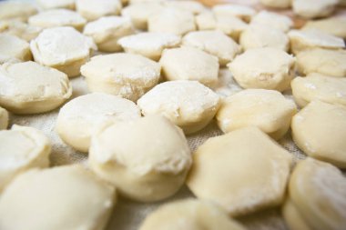 El yapımı ravioli hamur köfteleri kesme tahtasına dizilmiş ve un serpiştirilmiş. Lezzetli ev yapımı yemekler ve hazırlıklar. Yakın çekim, makro.