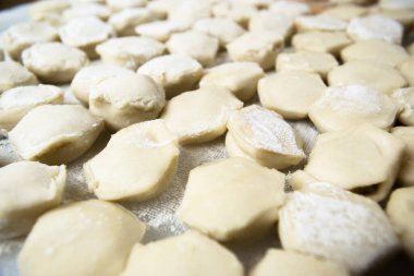 El yapımı ravioli hamur köfteleri kesme tahtasına dizilmiş ve un serpiştirilmiş. Lezzetli ev yapımı yemekler ve hazırlıklar. Yakın çekim, makro.