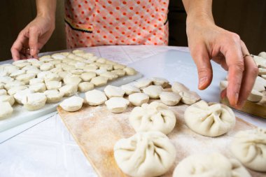 Kadının elleri, un ile kirletilmiş, düzgünce el yapımı, taze yapılmış hamur tatlısı, ravioli ve khinkali kesilmiş tahtalarda. Lezzetli ev yapımı yemekler. Beyaz arkaplan, yakın plan, seçici odak.