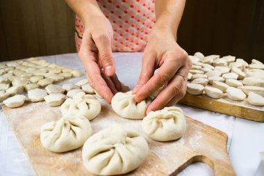 Kadının elleri, un ile kirletilmiş, düzgünce el yapımı, taze yapılmış hamur tatlısı, ravioli ve khinkali kesilmiş tahtalarda. Lezzetli ev yapımı yemekler. Beyaz arkaplan, yakın plan, seçici odak.
