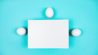 4k Three white eggs appear and hide behind a sheet of white paper. Happy Easter Day Concept. Light blue background. Template for text. Stop motion animation. Copy space.