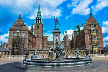 Hillerod, Danimarka - 1 Haziran 2019: Frederiksborg Şatosu 'nun ön bahçesinde bulunan deniz tanrısı Neptune Çeşmesi yakınlarında turistler. Saray kompleksi ve turistik cazibe.