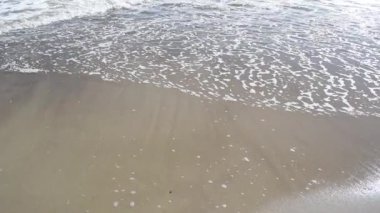 Deniz sörfünün beyaz köpüğünü kapat. Kumsalda deniz dalgaları dalgalanır. Deniz manzaralı yakın plan. Uzayı kopyala Doğal arkaplan, metin şablonu. Deniz tatili ya da çevre kavramı.