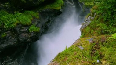 Slettafossen şelalesinin fırtınalı suları kayalarda bir kanal açmıştı. Yeşil ormanın Rocky yaz manzarası. Norveç.